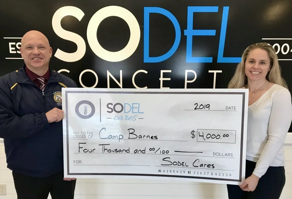 SoDel Cares, the philanthropic arm of SoDel Concepts, recently donated $4,000 to Camp Barnes. Lindsey Barry, Controller for SoDel Concepts, presents he check to Master Corp. James Hatfield of Camp Barnes in SoDel Concepts’ Rehoboth Beach office. [PH…