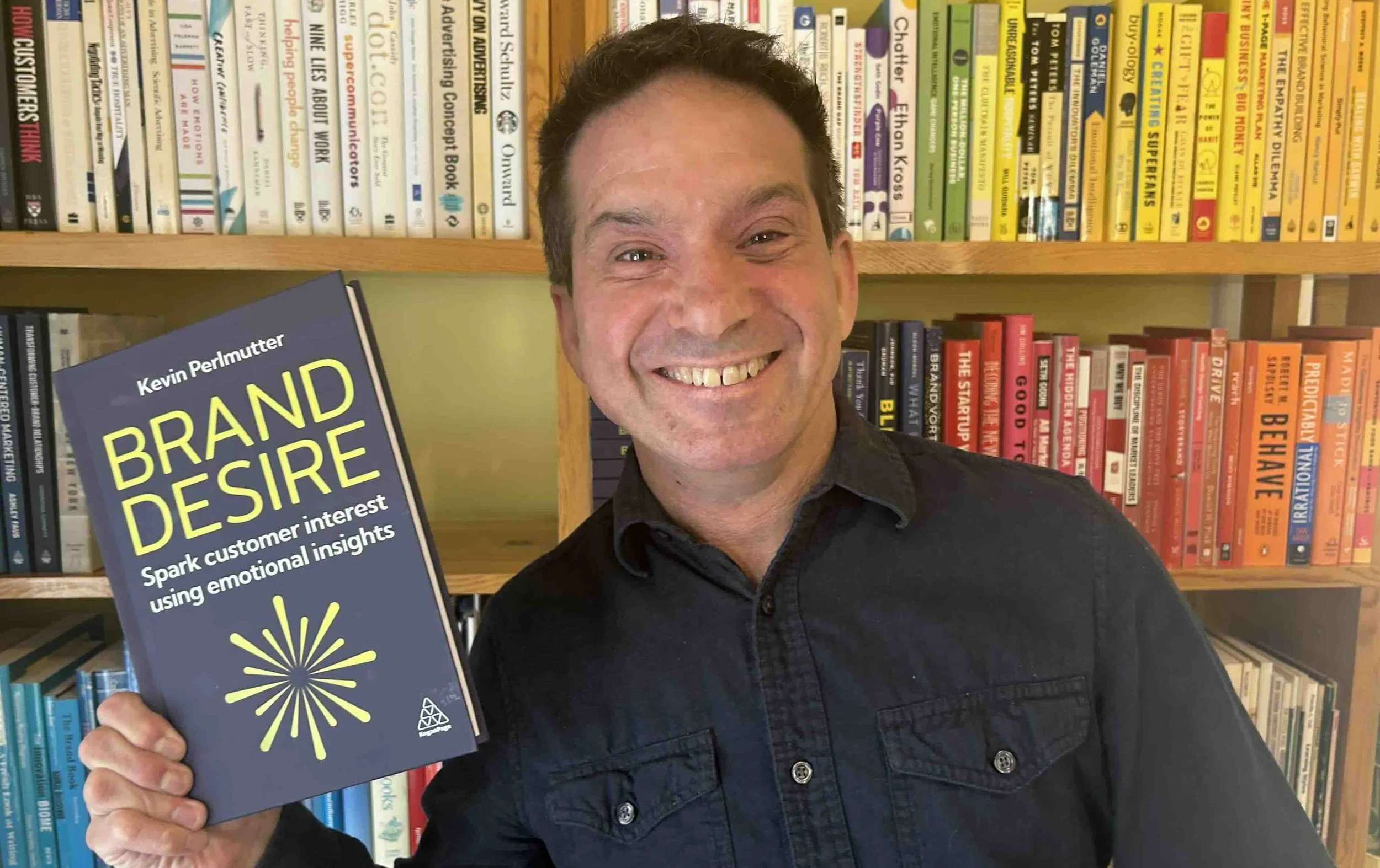 Kevin Perlmutter holding a copy of Brand Desire: Spark Customer Interest Using Emotional Insights