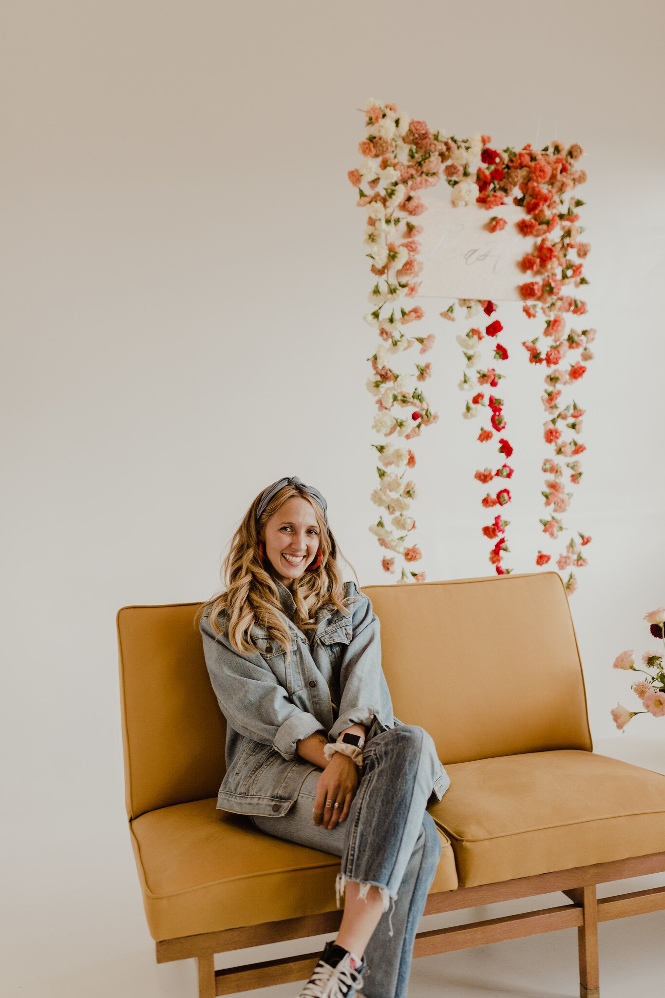 posing in front of photo wall with hanging floral back drop.jpg