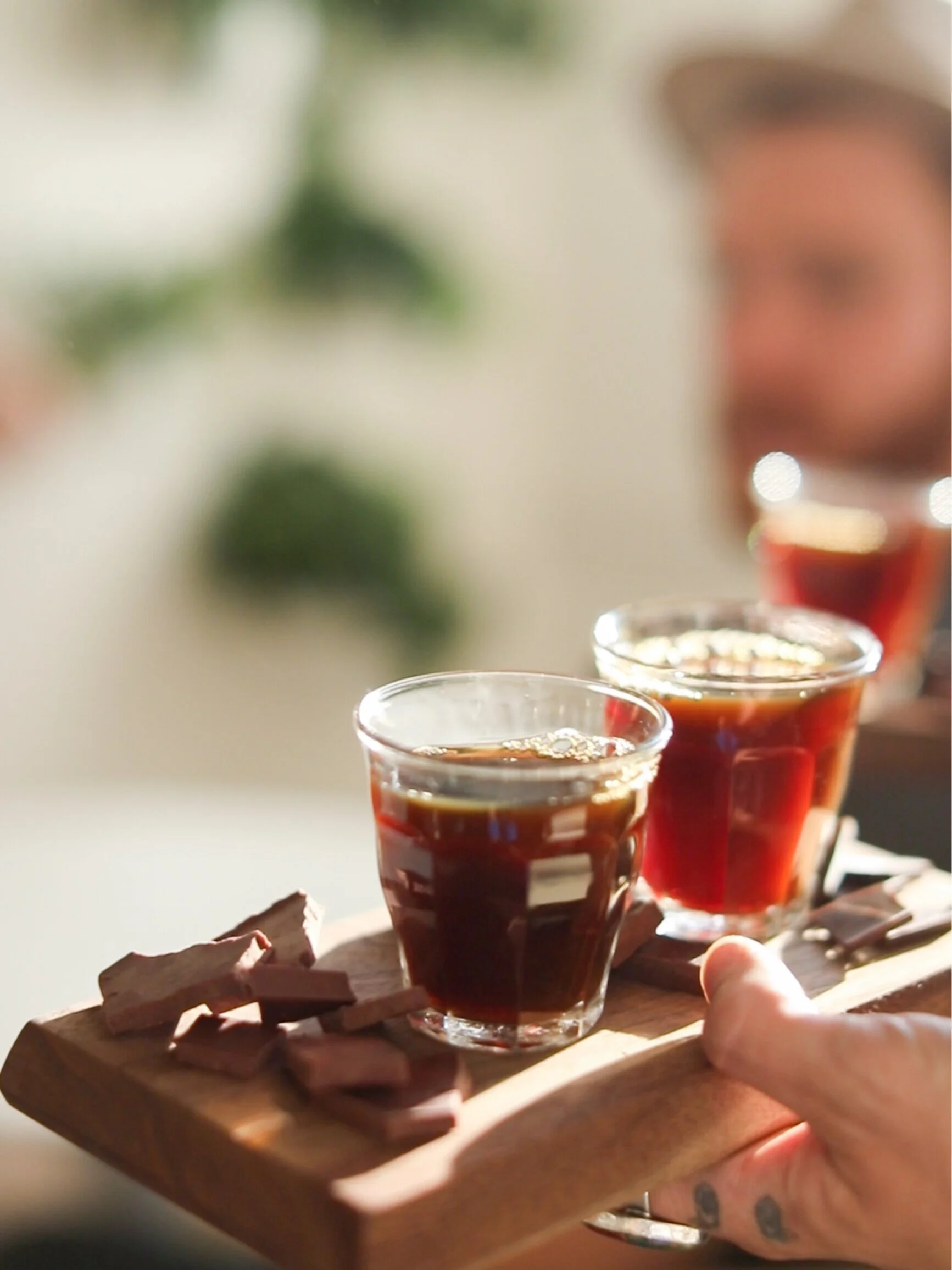 hand holding wood board with chocolate pieces and coffee glasses