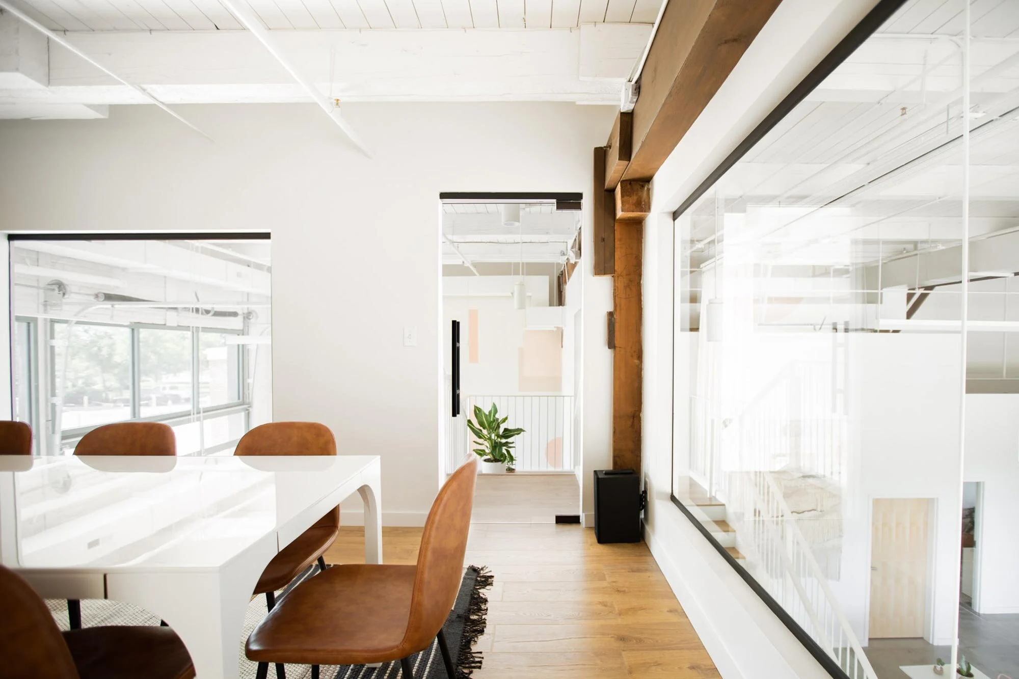 Pleather modern chairs around white table with large windows and glass door in cozy white-walled Realm Mezzanine