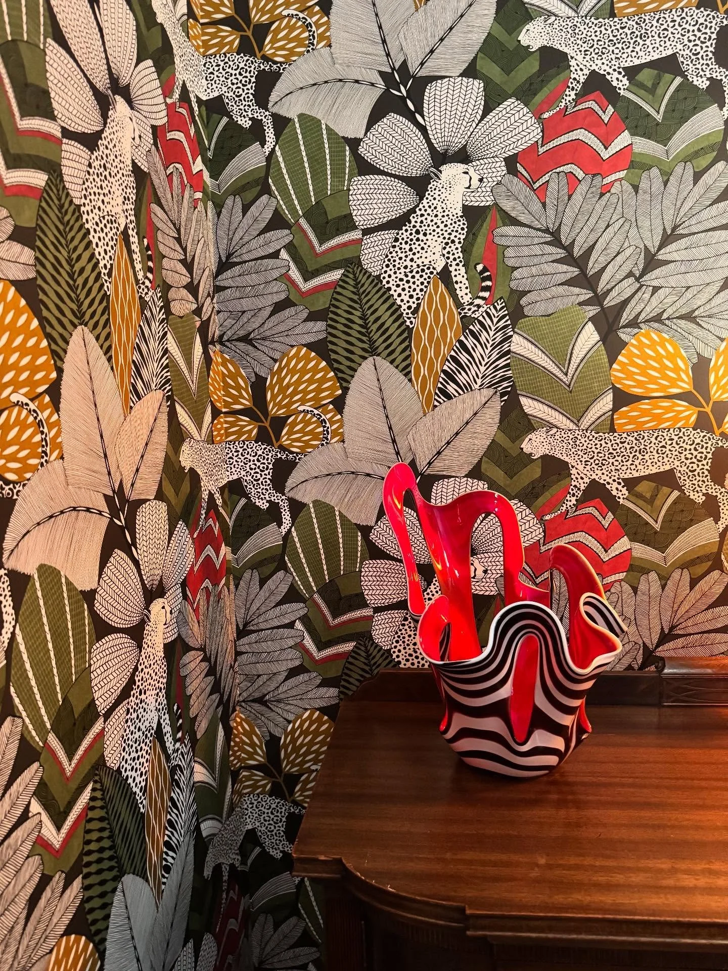 This powder room packs a punch with bold jungle wallpaper, layered pattern, and playful color. scroll for the before 🐅