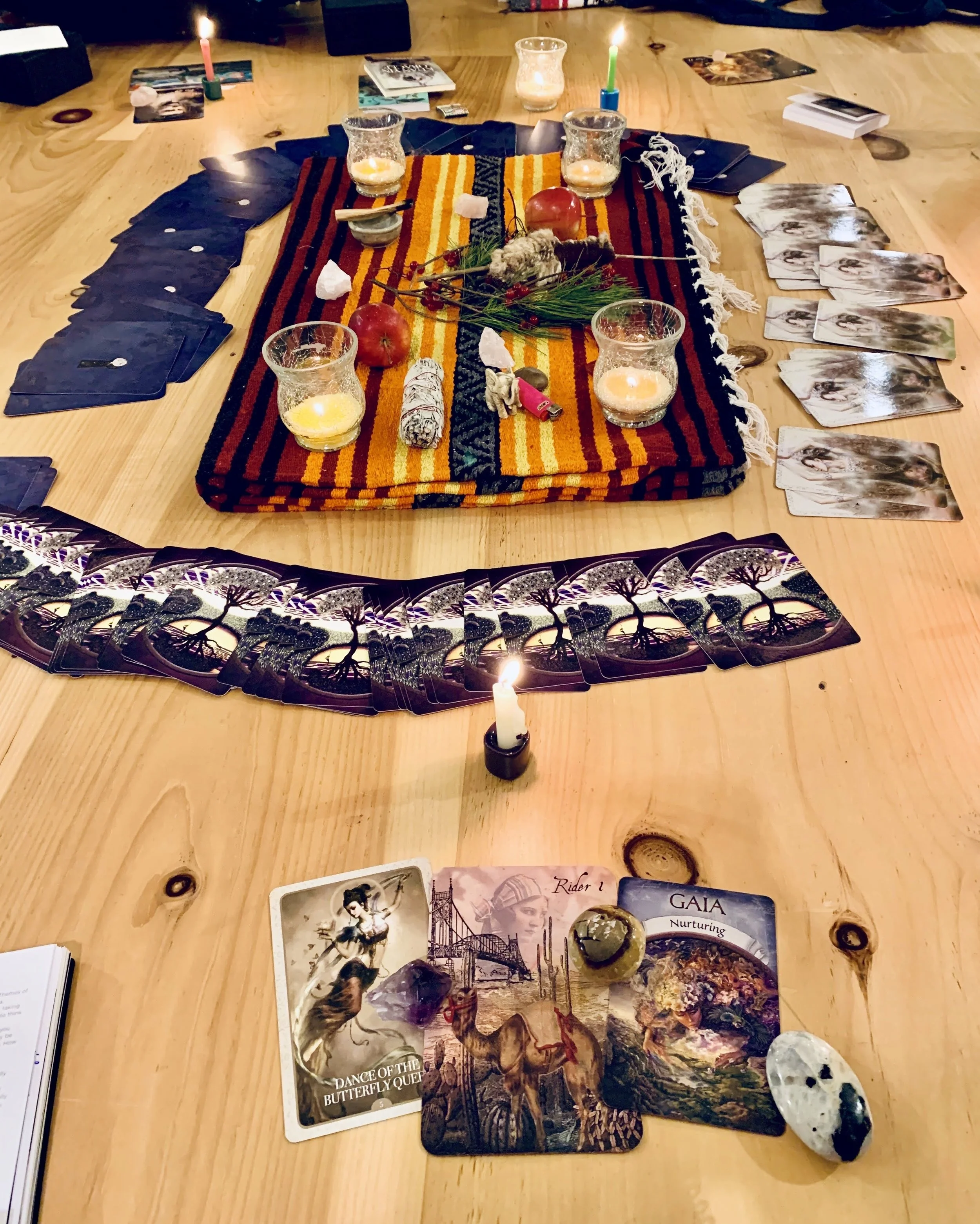 A table set for a spiritual or tarot reading session with tarot cards, candles, crystals, and spiritual items.