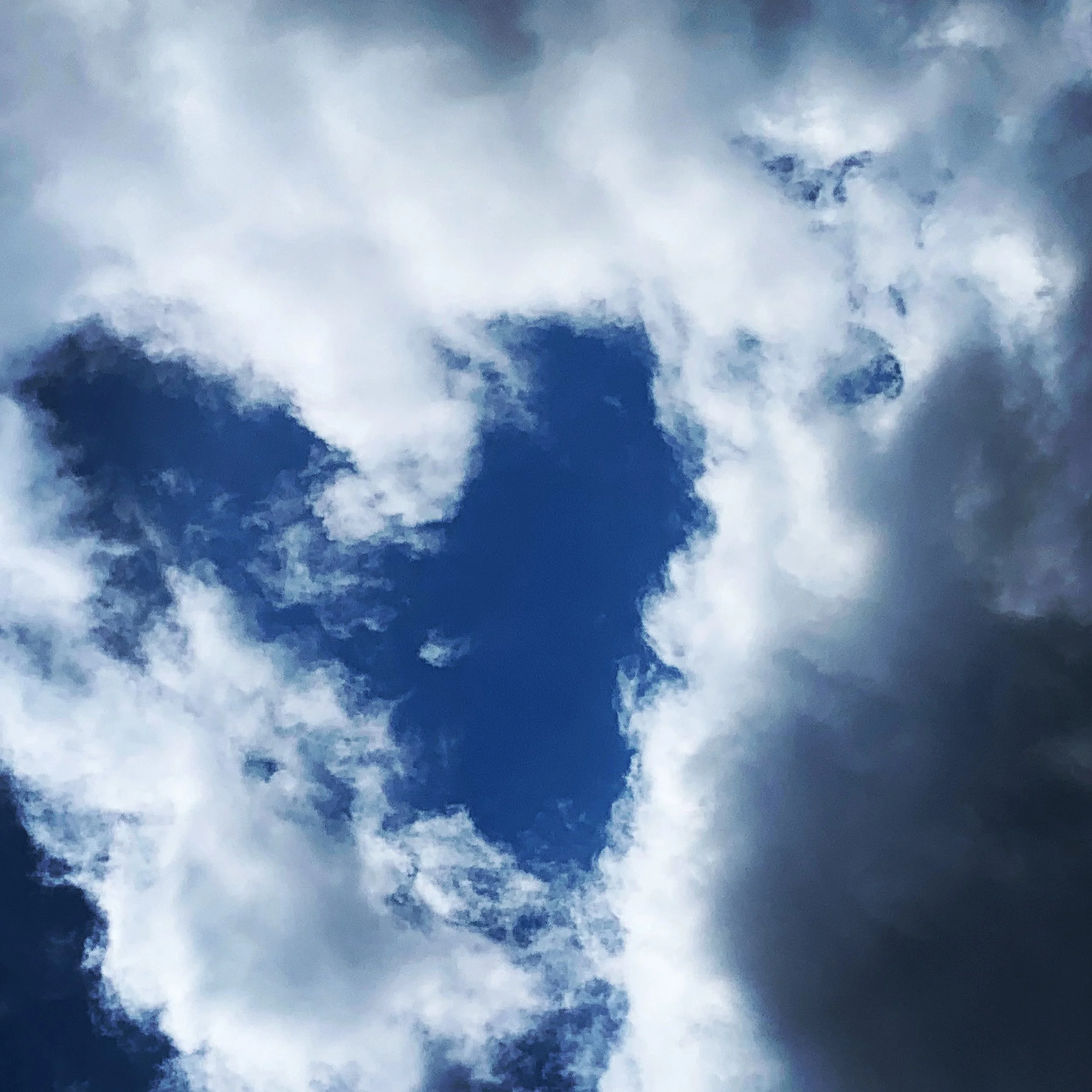 Partly cloudy blue sky with patches of white and gray clouds.