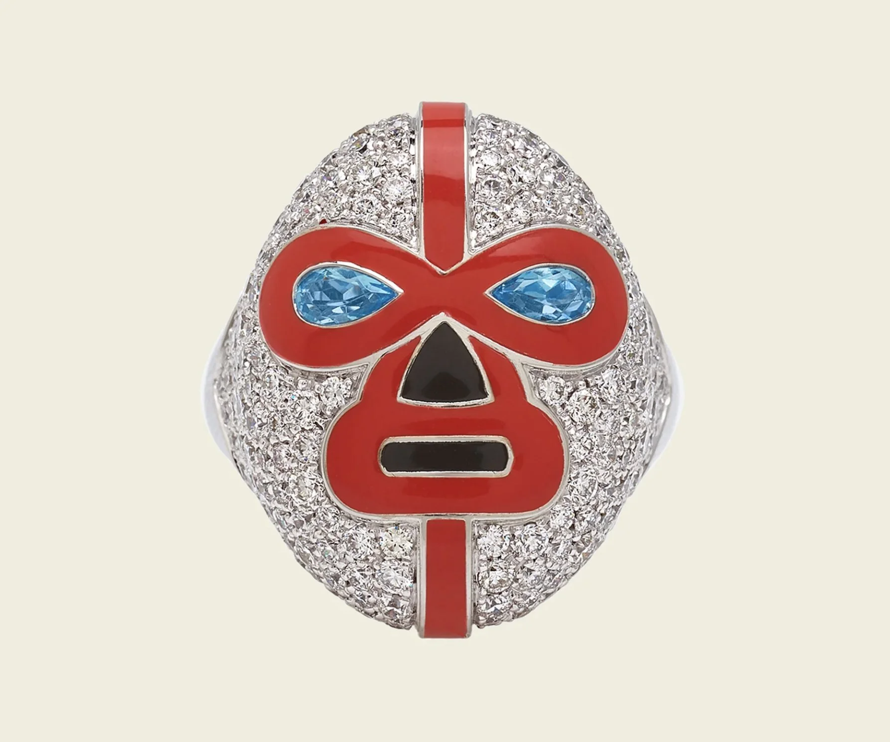 A jewelry piece featuring a skull design adorned with numerous small diamonds, with a red and black mask motif and blue gemstone eyes.