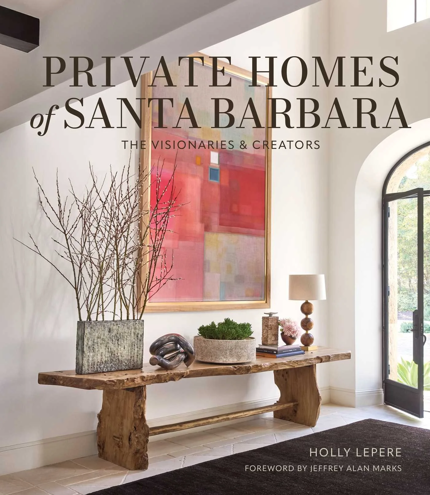 Cover of the book 'Private Homes of Santa Barbara' by Holly Lepere, with a photograph of an interior space featuring a rustic wooden console table decorated with artistic objects, a large potted plant with bare branches, and a colorful abstract painting on a white wall, with a partly open black-framed door and a window allowing natural light.