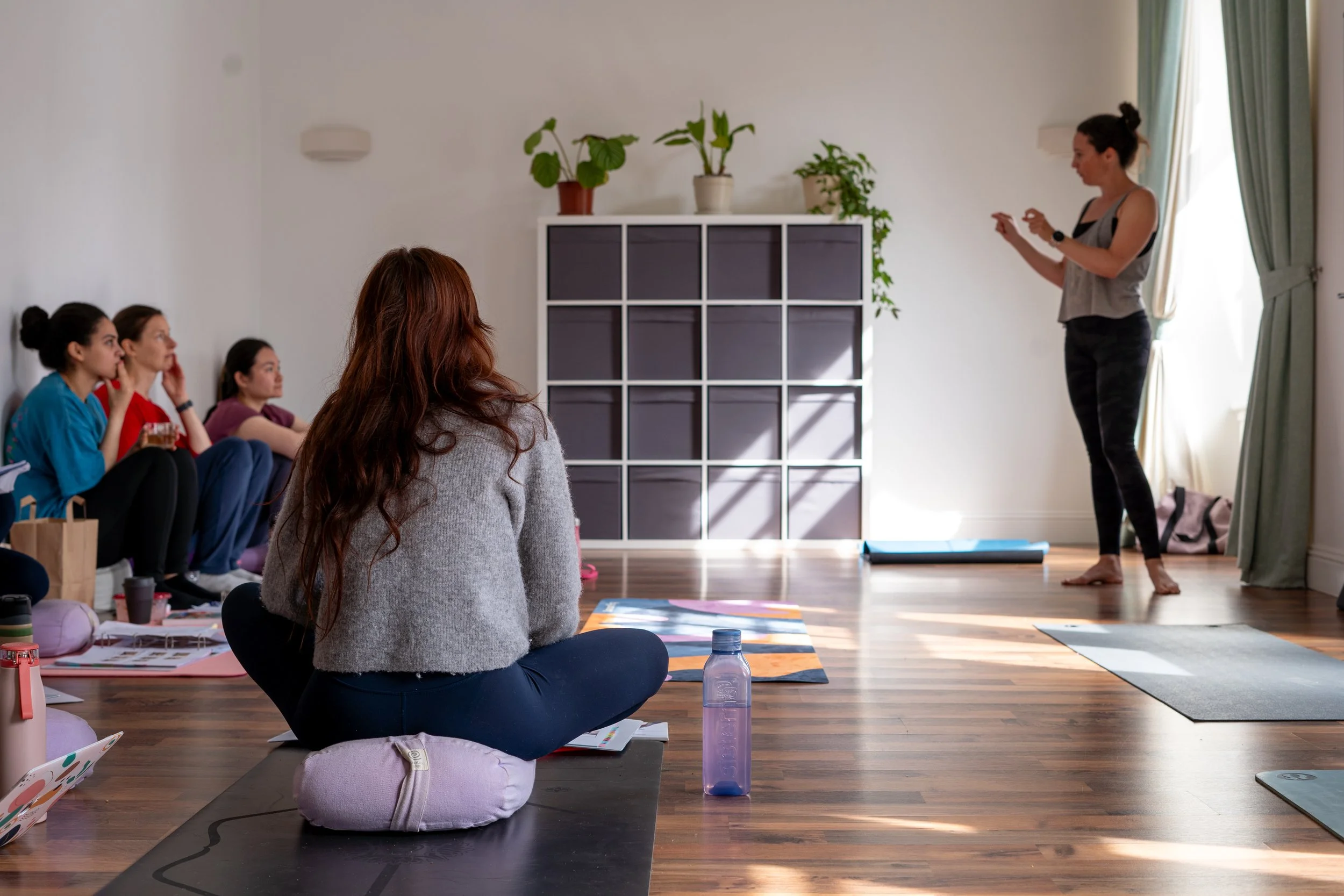 Julia Clarke explaining something to trainee yoga teachers in sunny studio