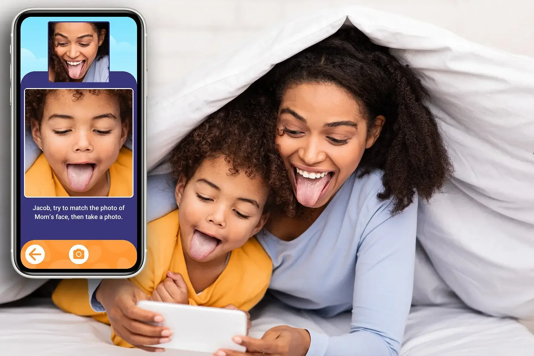 Mother and child under a blanket taking a playful selfie on a smartphone, both sticking out their tongues.