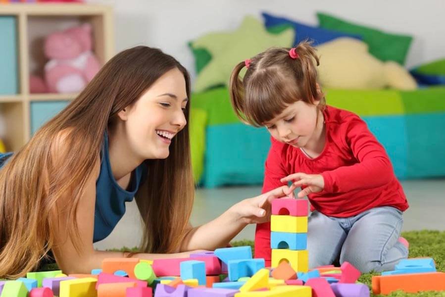 Mom and daughter play together and stack colorful blocks.