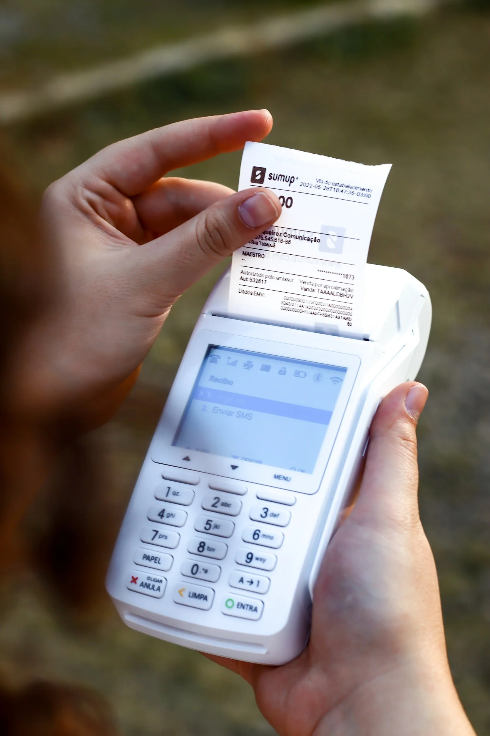 Person holding a SumUp card reader printing a receipt.