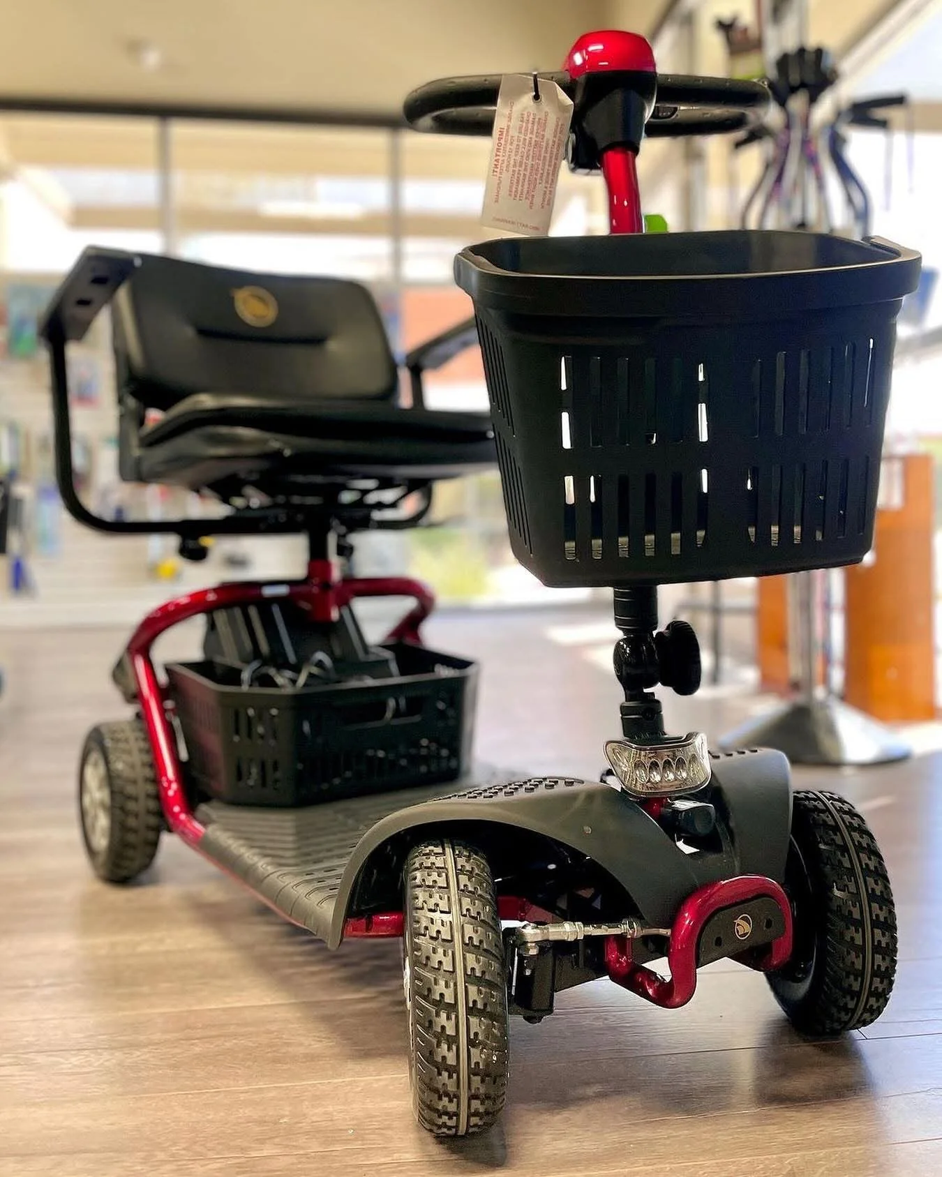 A black and red four-wheeled scooter with a black basket attached to its steering column.