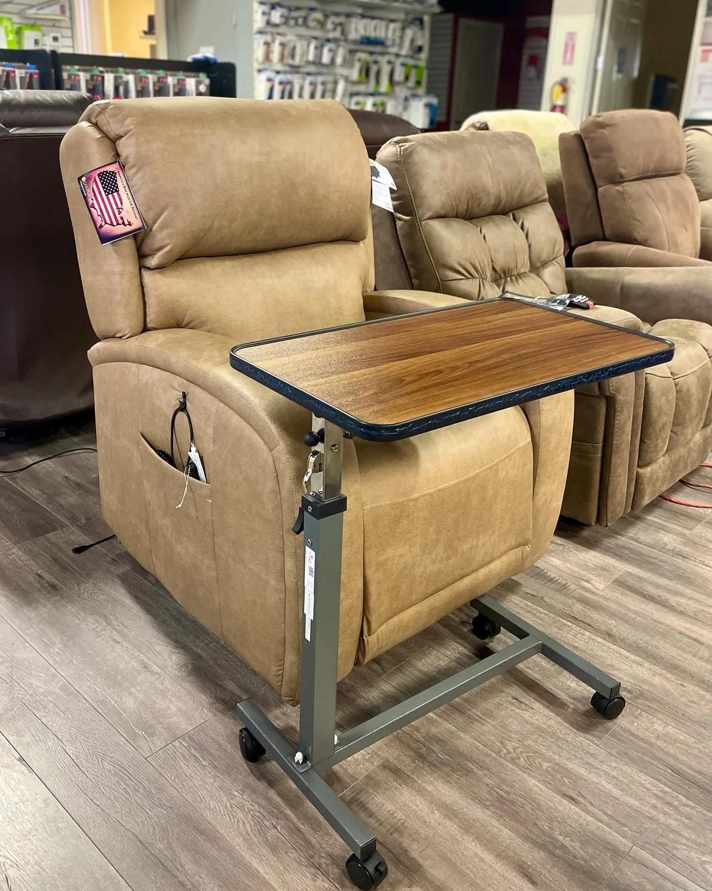 Recliner chair with an attached tall, adjustable wooden tray table on wheels in a furniture store.