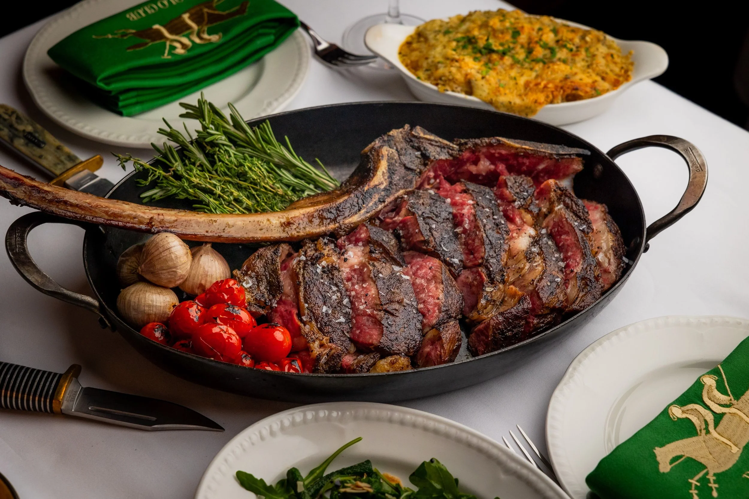 Grilled Black Angus tomahawk served with rosemary, roasted garlic and cherry tomatoes.
