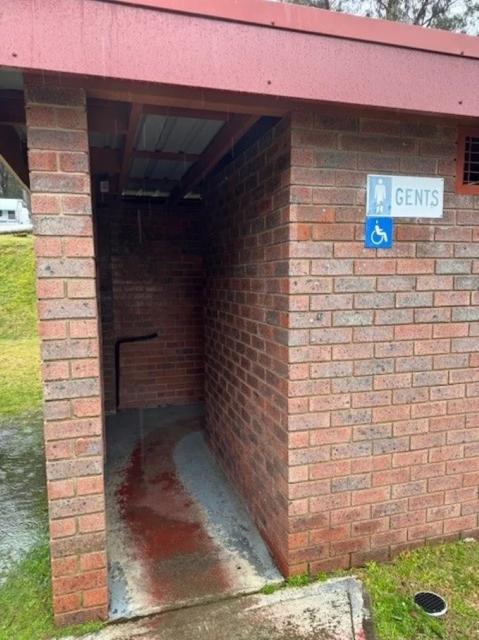 An open entry way through a red brick building that has two signs, one saying gents and the other a blue background and white figure and wheelchair