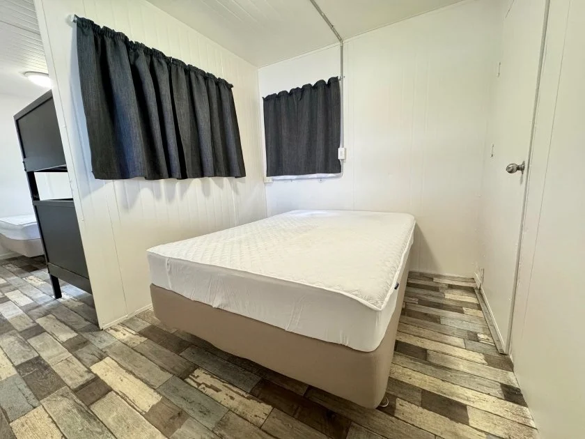 A brown-white double ensemble bed and blue-grey curtained windows feature in the main bedroom