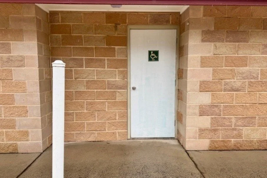 A large white door and white pole on the front of a cream brick building.