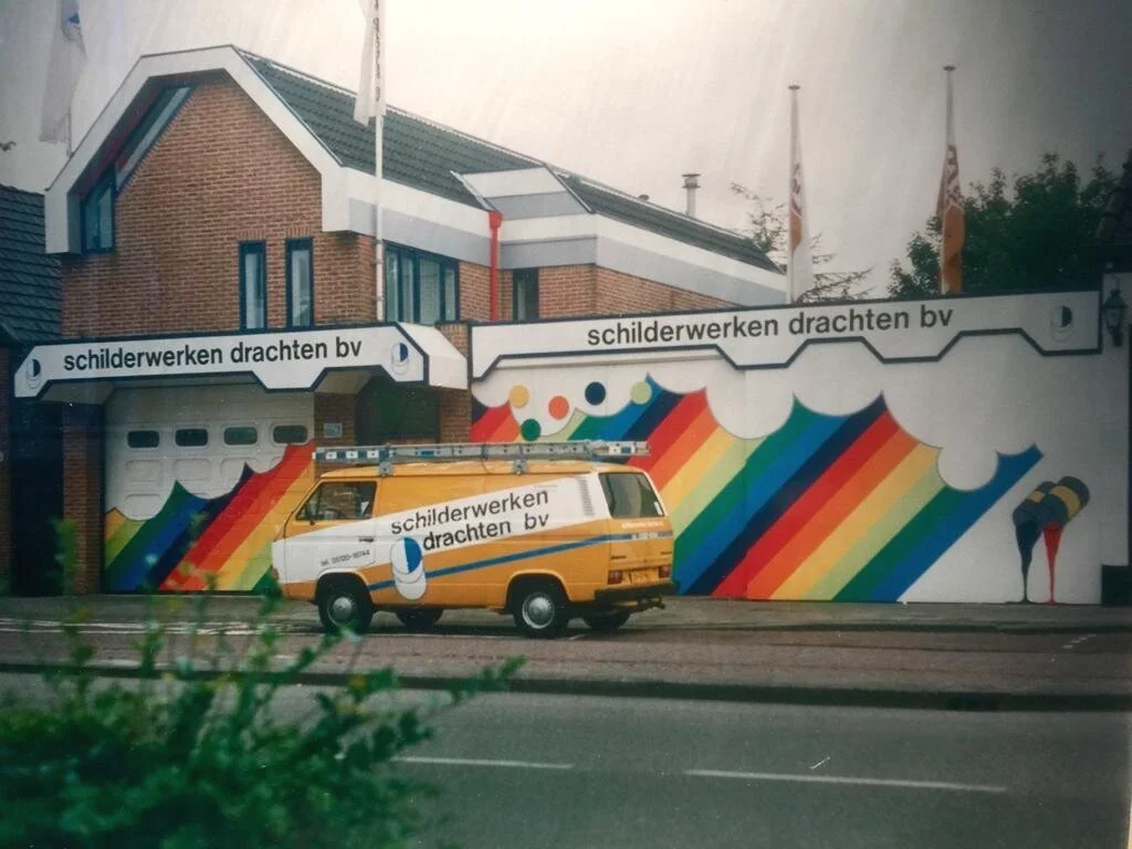 Schilderwerken Drachten BV in de jaren 80 aan de Zuidkade in Drachten met regenbooggevel en gele Volkswagen bedrijfsbus