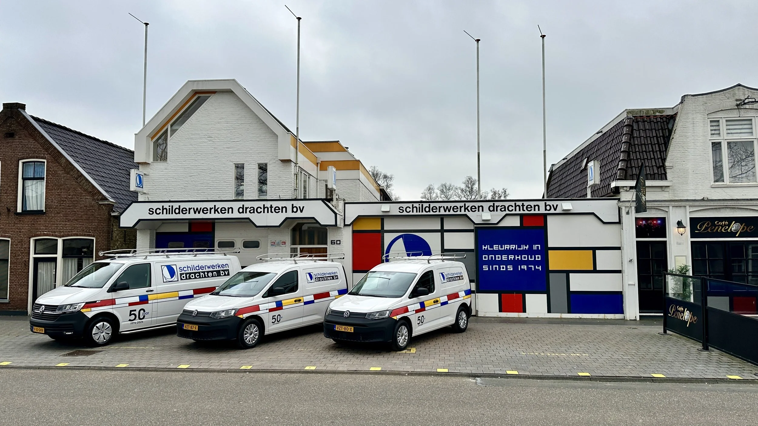 Bedrijfswagens van Schilderwerken Drachten BV tijdens 50-jarig jubileum voor het pand aan de Zuidkade in Drachten