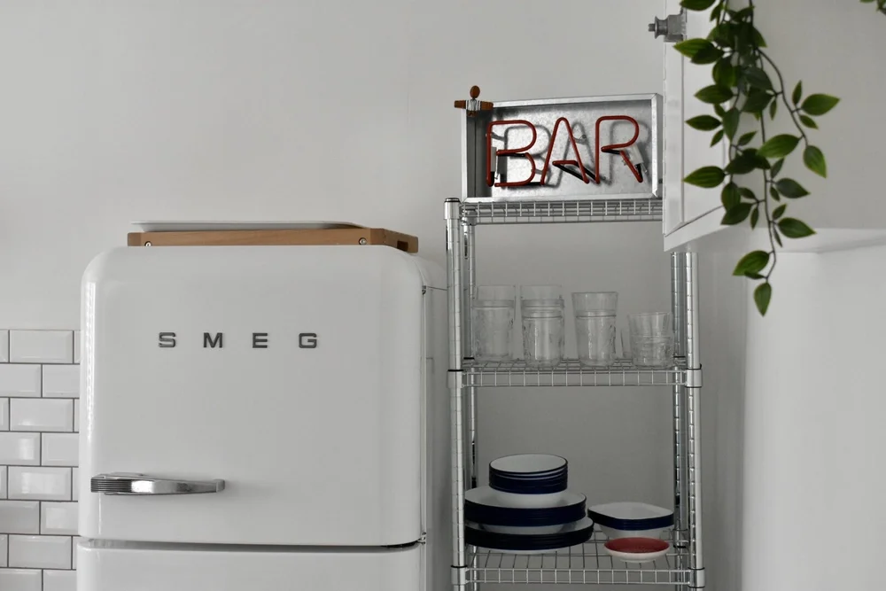 A smeg fridge and neon bar sign