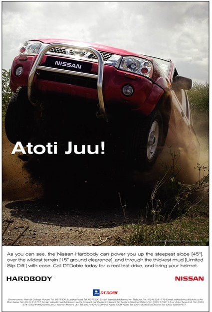 Red Nissan Hardbody pickup truck driving over rugged terrain with dust and dust clouds behind it, demonstrating off-road powerabilities.