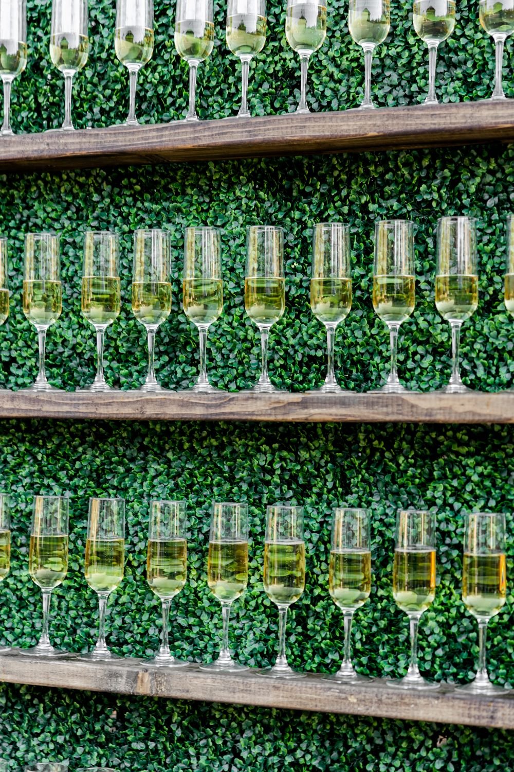 How to nail your wedding rehearsal dinner toast, classic wooden shelves with greenery in the background & champagne glasses on them, let's get rehearsed