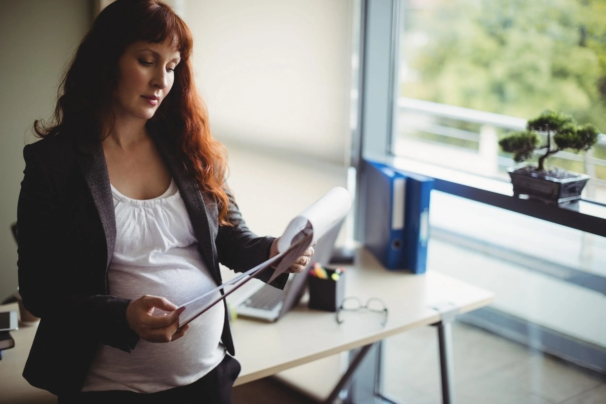 pregnant-businesswoman-reading-paper-documents-scaled.jpg