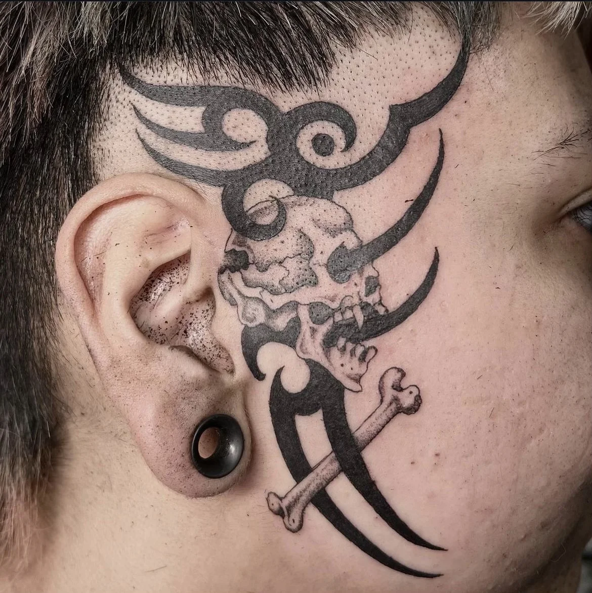 A fine line tattoo of a skull with tribal on a face by Kai Trevino in Texas