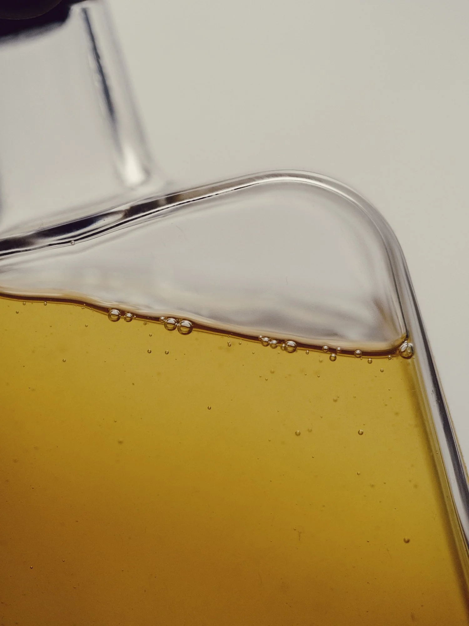 Close-up of a glass container with yellow liquid and small bubbles inside.