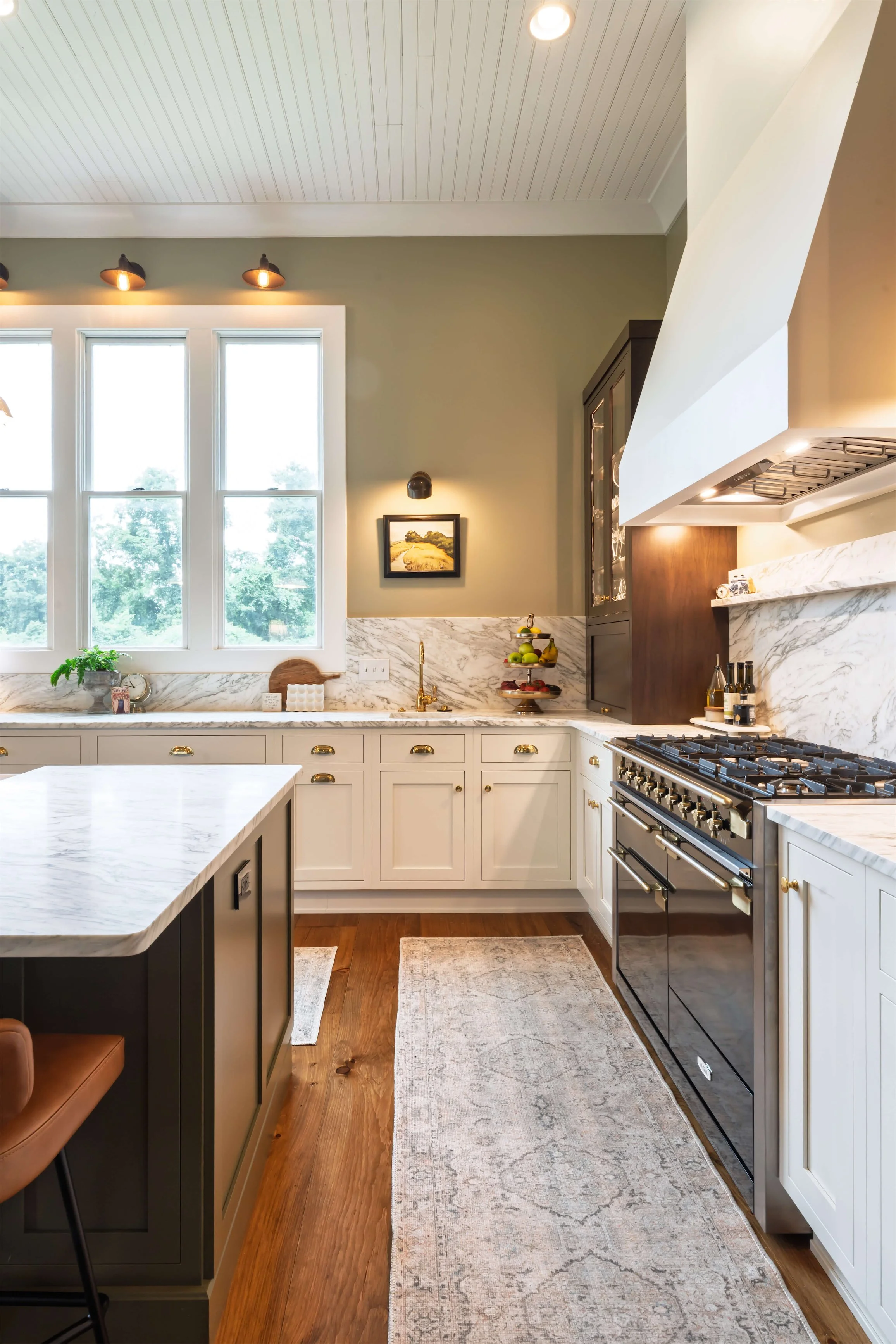 A kitchen featuring inset cabinetry and a hood above the stove. A wall sconce is over the bar sink.