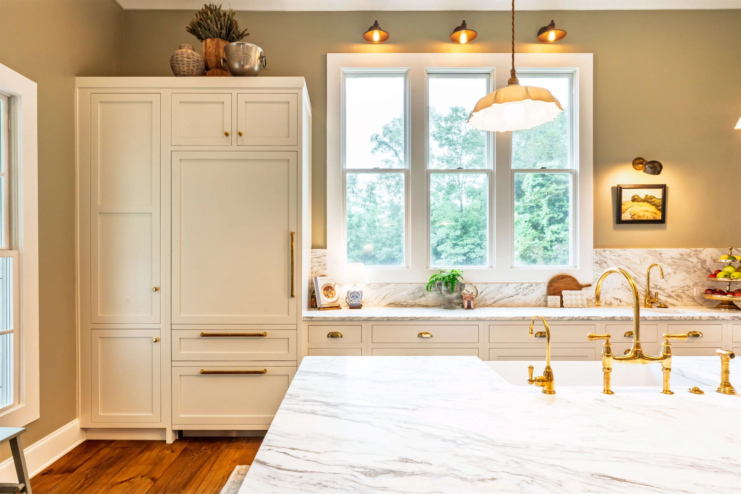 A kitchen featuring a built-in refrigerator, panel ready refrigerator, an island with marble countertops and large windows