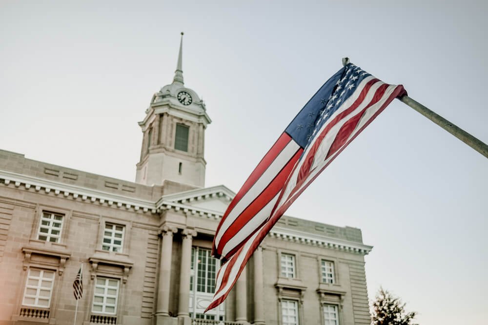 American flag in front of a historic courthouse with clock tower
