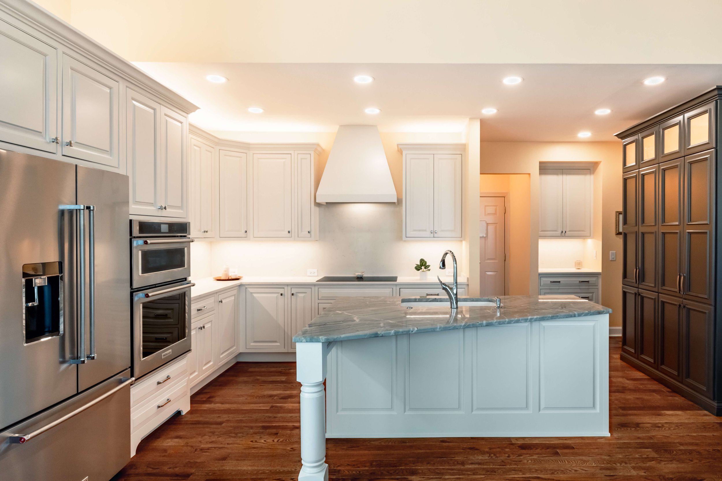 Renovated kitchen with white cabinets, stainless steel appliances, and marble island