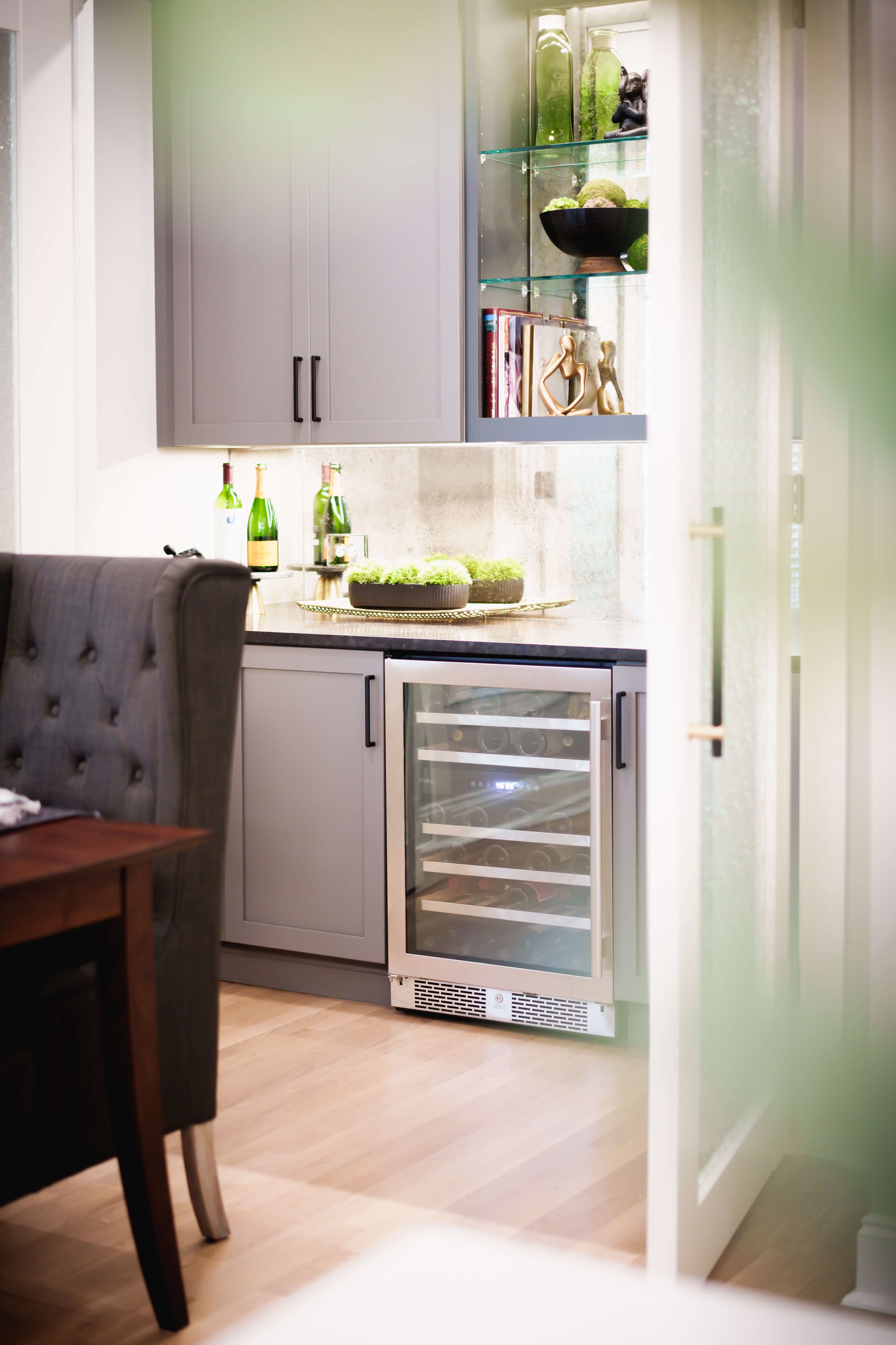 Kitchen with gray cabinets, wine cooler, and decorative items on countertop and shelves.