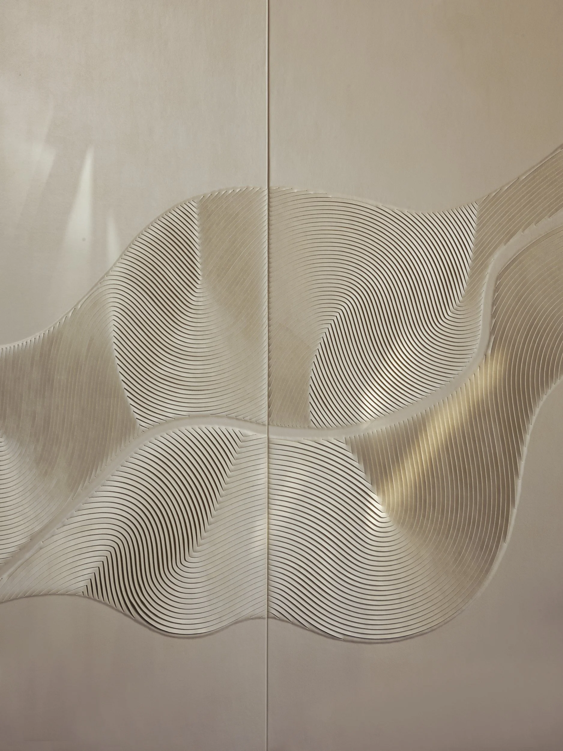 Close-up of a textured, decorative wall panel with flowing curved lines and layered patterns in cream and beige tones.