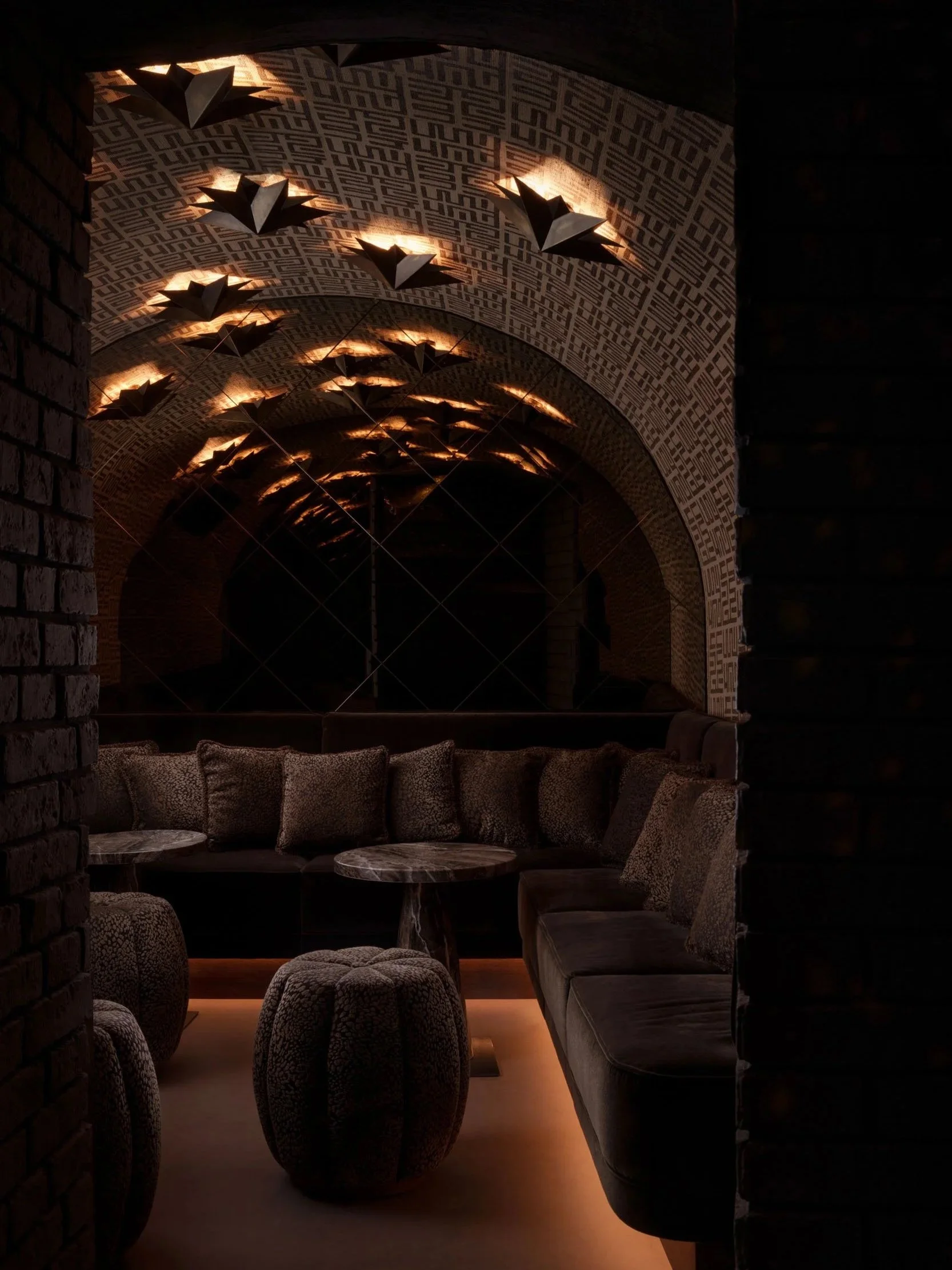 Luxury lounge in Mayfair, London, featuring moody ambient lighting, plush seating, and intricate vaulted ceiling design, captured by a London interior photographer.