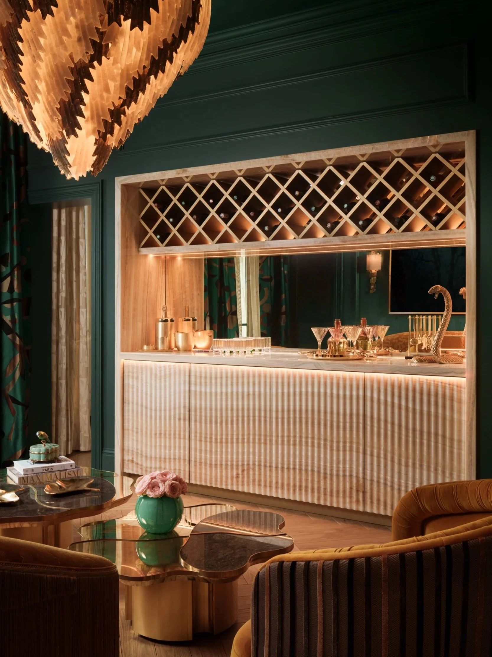 Luxurious home bar interior in Mayfair, featuring a statement chandelier, illuminated marble counter, and sophisticated dark green decor, captured by a London interior design photographer.