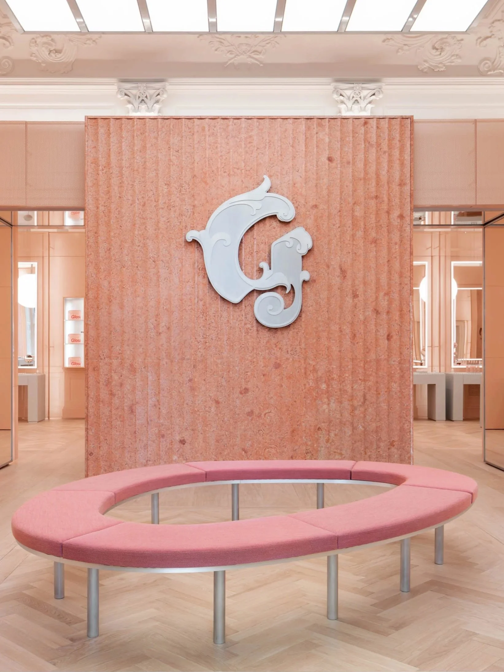 Modern retail interior in Oxford Circus, featuring a pink circular bench, textured stone wall, and elegant branding details. Captured by a London architecture photographer.