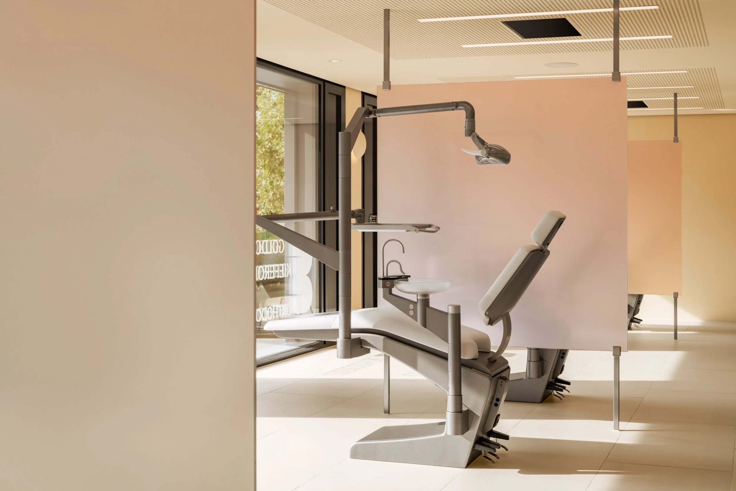 Dental examination chair with overhead light and attached sink in a modern, bright dental clinic.