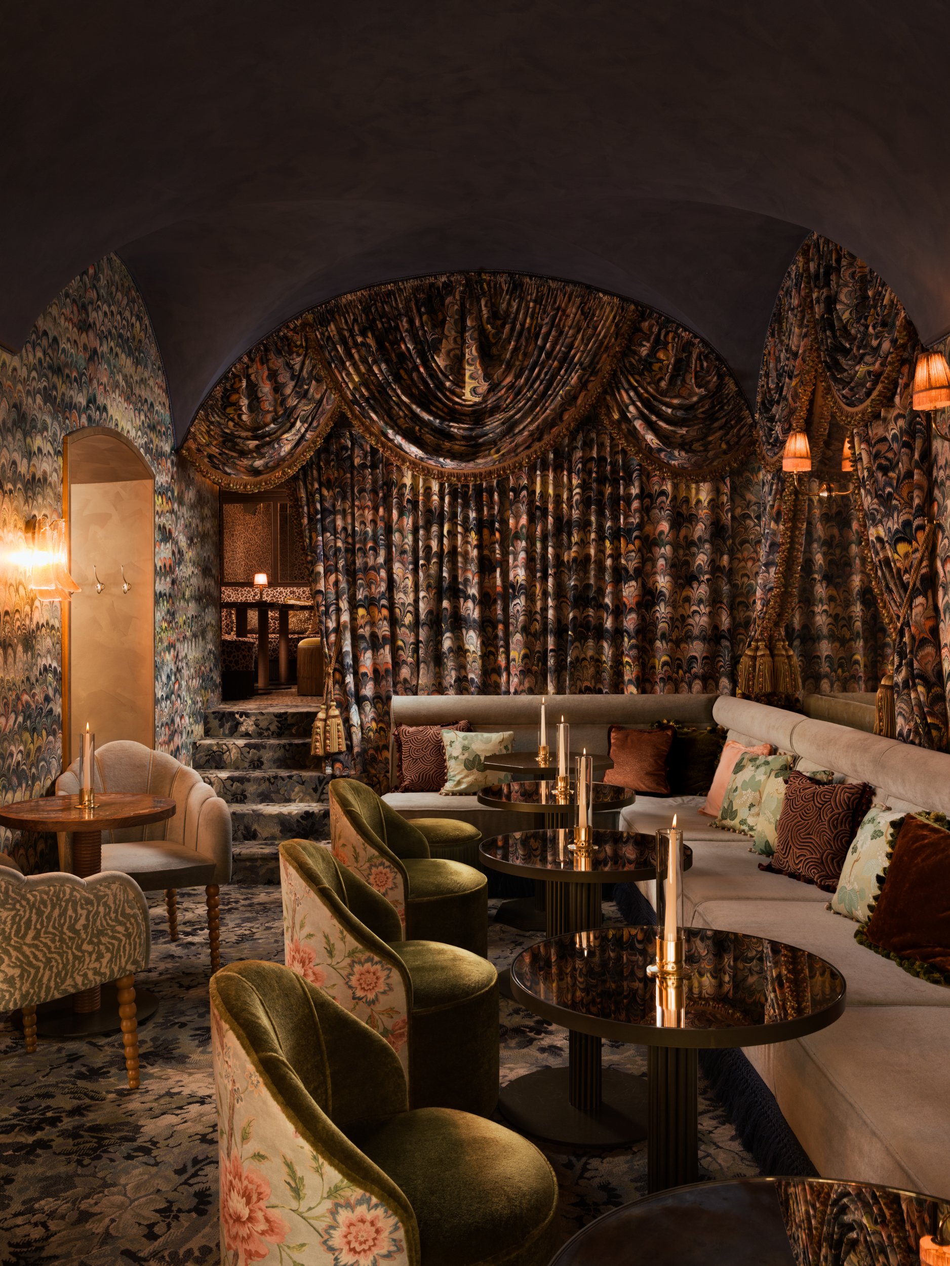 ntimate lounge with layered patterned drapery, arched ceiling and candlelit tables, photographed by a London interior photographer specialising in hospitality and interior design photography.
