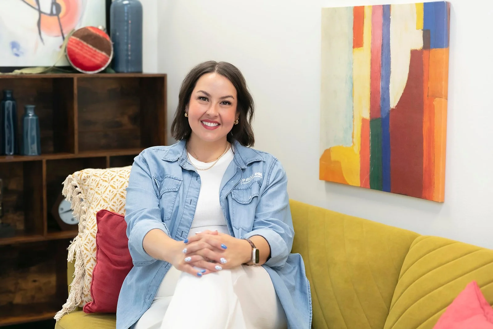 Olivia Miller sitting on a yellow couch smiling