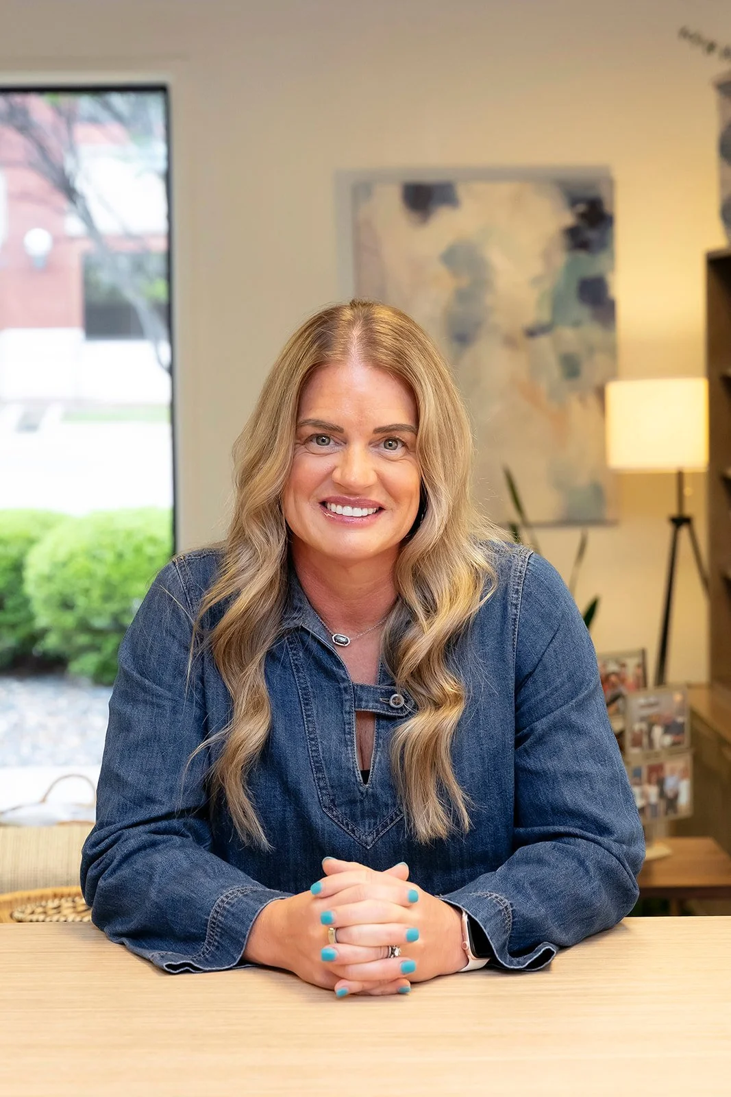 DeAnn Roberson smiling in a denim dress and blonde hair. 