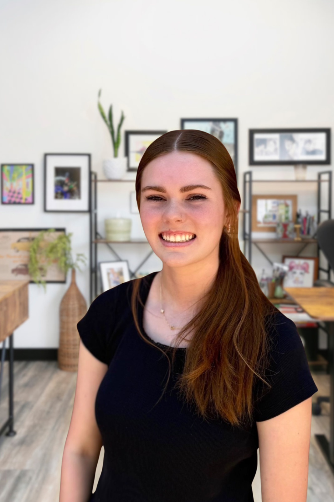 Camille smiling against wall of pictures.