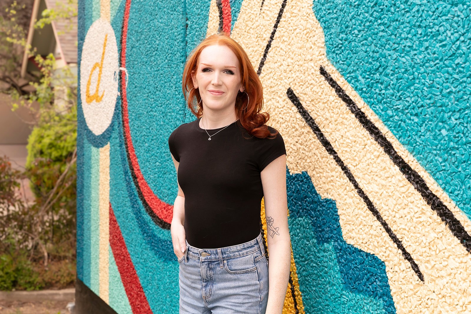 Noelle Carroll against a colorful mural in a black shirt
