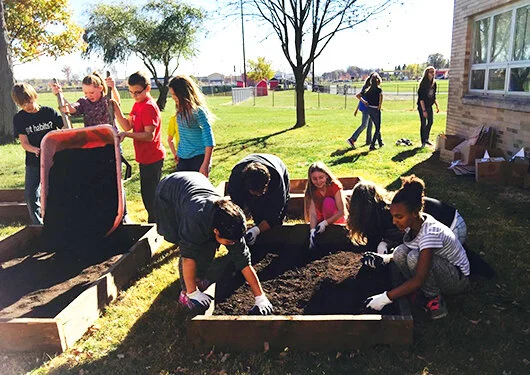 Students fill raised beds to 8 inches.