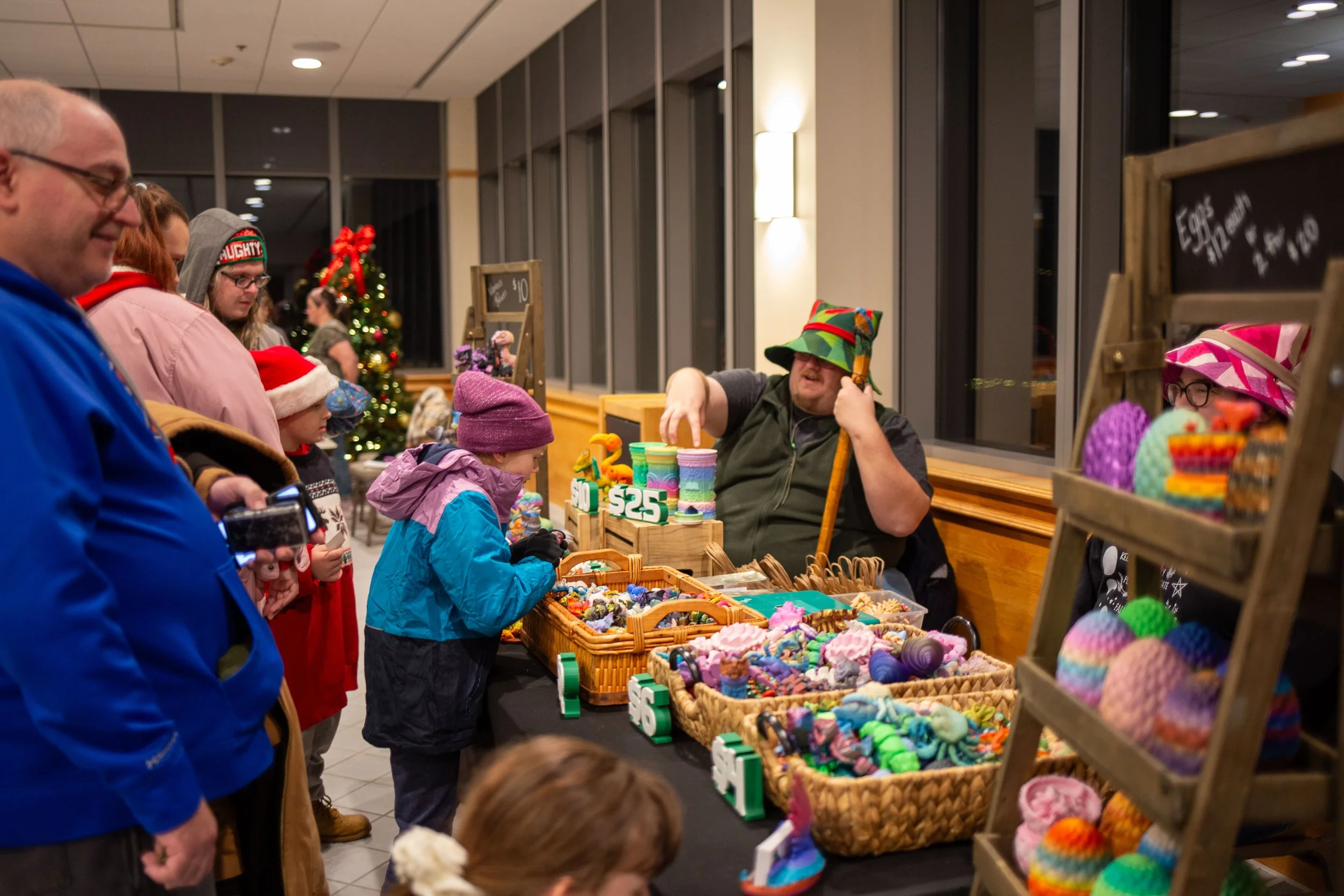 Families with children stop by a table of 3D printed animals.