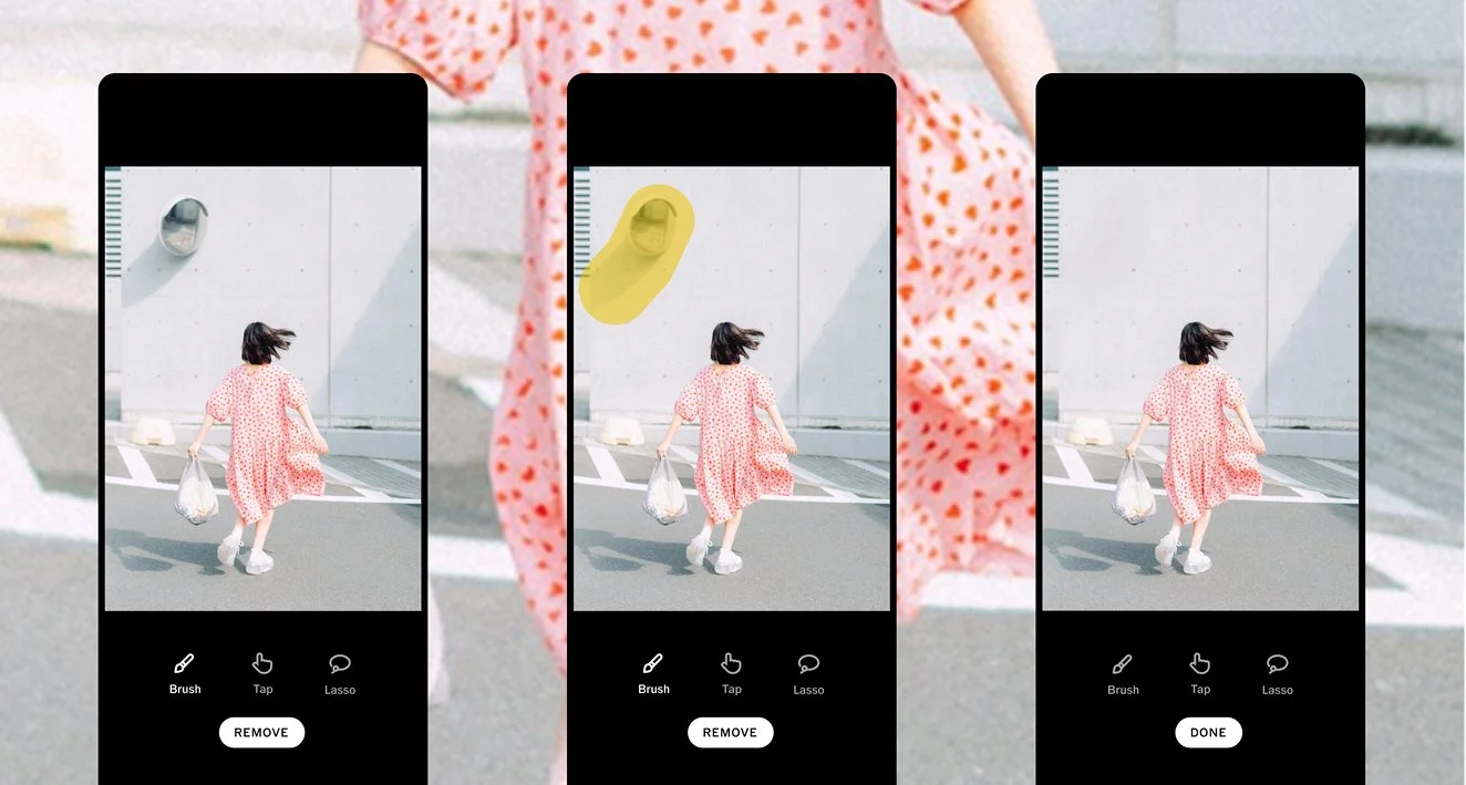 The image shows a woman walking away from the camera, wearing a pink polka-dot dress and holding a plastic bag, with her hair blowing in the wind. She is on a street with a gray building in the background.