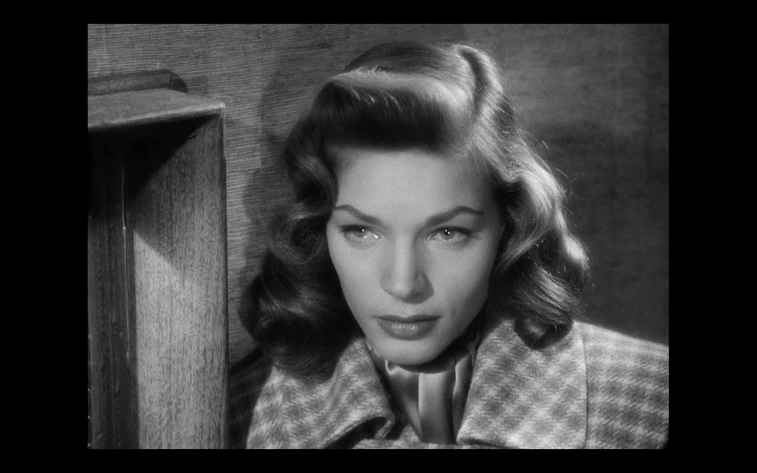 Lauren Bacall’s character gets a bit teary-eyed at the thought of Humphrey Bogart’s character leaving. Notice the perfect pin-curl waves and classy coat!