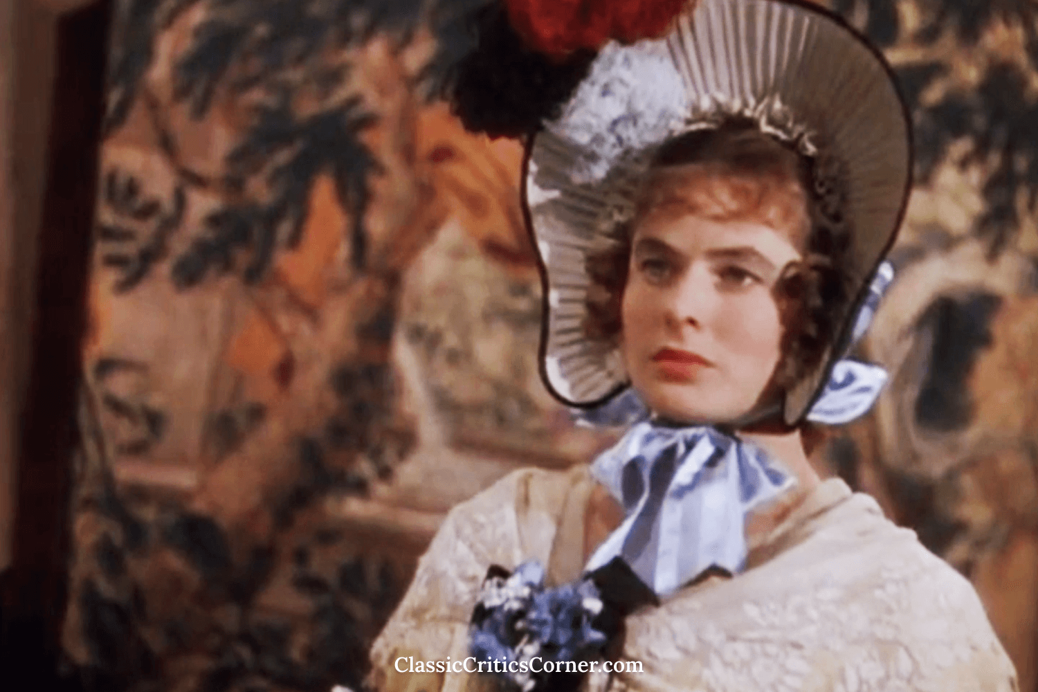 Ingrid Bergman’s character Lady Henrietta is wearing is a yellow dress and lace shawl. Her dress is decorated with layers of bows, lace, and… more roses, not to mention colored pom poms!!&nbsp;&nbsp;To top off this dizzy combination, is a bright bon…