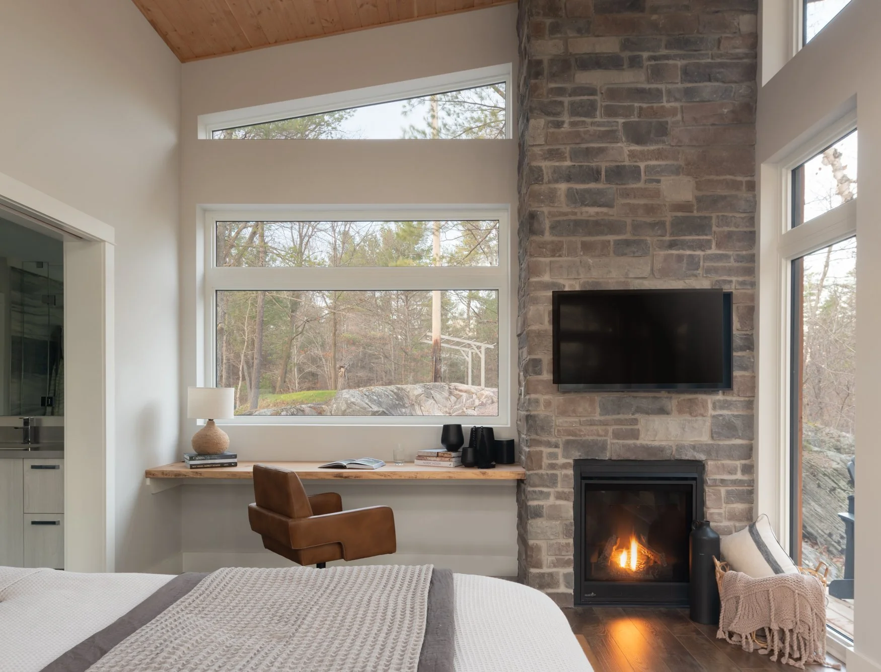Primary bedroom with built-in desk and stone fireplace