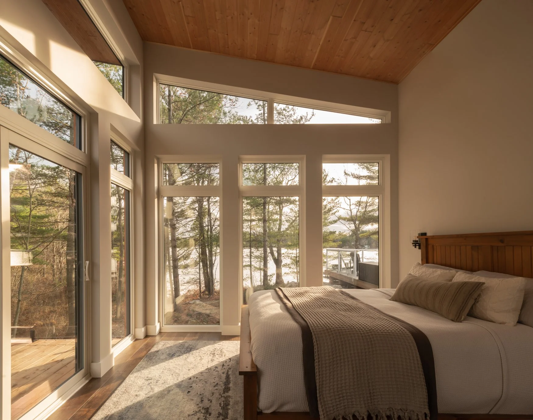 Primary bedroom with full height windows capturing picturesque views of Tea Lake in Muskoka